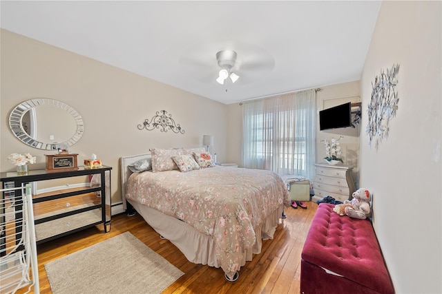 bedroom featuring ceiling fan, baseboard heating, and hardwood / wood-style floors