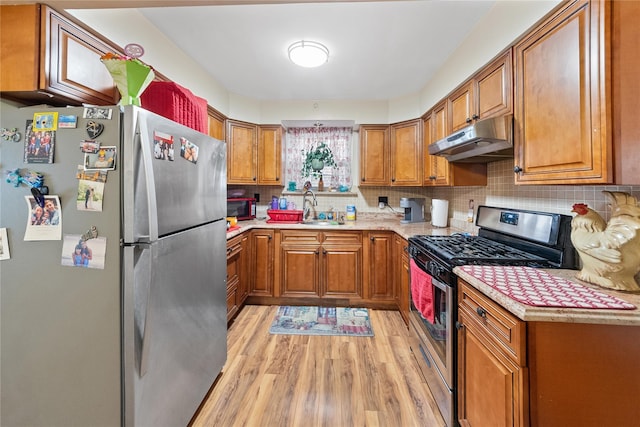 kitchen featuring brown cabinets, under cabinet range hood, stainless steel appliances, and light countertops