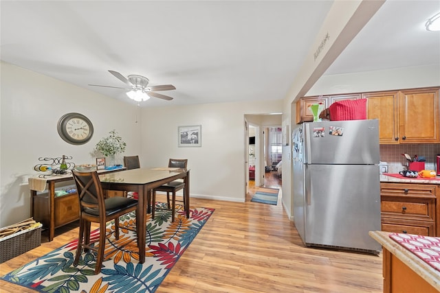 dining room featuring a ceiling fan, light wood-style flooring, and baseboards