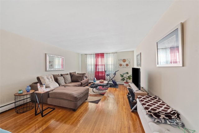 living area with a wealth of natural light, a baseboard radiator, and hardwood / wood-style flooring