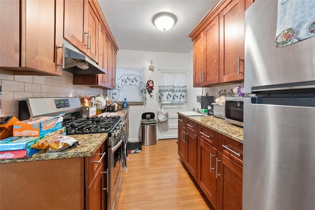 kitchen featuring stainless steel appliances, light wood-type flooring, brown cabinets, and under cabinet range hood