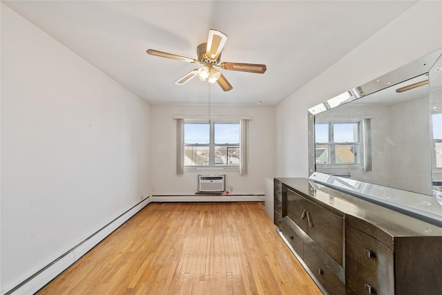 empty room featuring light wood-type flooring, a baseboard heating unit, a ceiling fan, and a wall mounted air conditioner