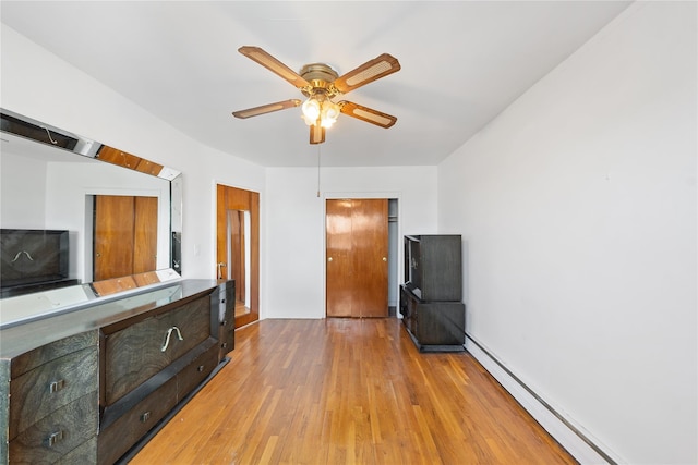 interior space with light wood finished floors, a baseboard radiator, and a ceiling fan