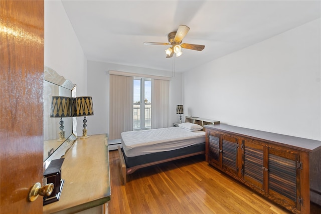 bedroom with a baseboard radiator, ceiling fan, and wood finished floors