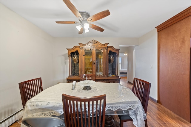 dining area featuring a baseboard heating unit, ceiling fan, baseboards, and wood finished floors