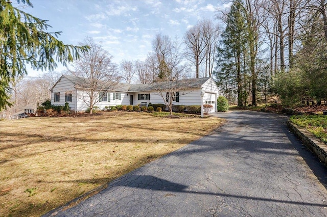 view of front of house with an attached garage, aphalt driveway, and a front yard