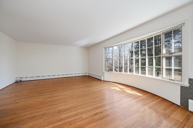 spare room with a baseboard heating unit, plenty of natural light, and light wood-style flooring