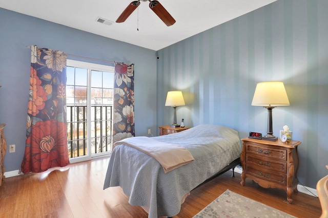 bedroom with visible vents, ceiling fan, wood finished floors, baseboards, and wallpapered walls