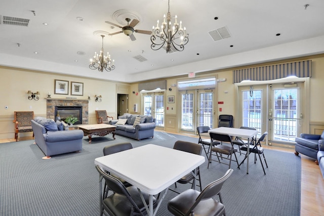 dining room featuring a wealth of natural light, french doors, a decorative wall, and a stone fireplace