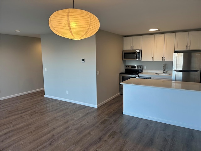 kitchen featuring baseboards, appliances with stainless steel finishes, dark wood-style flooring, light countertops, and a sink