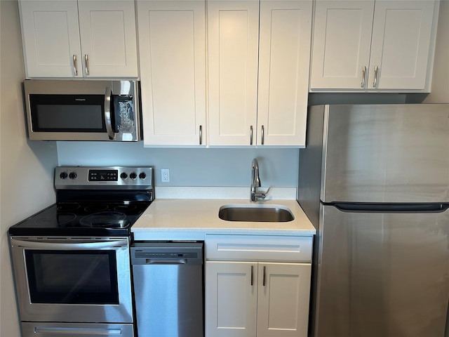 kitchen featuring stainless steel appliances, a sink, light countertops, and white cabinetry