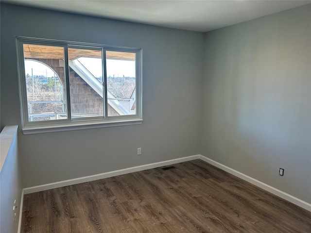 empty room featuring visible vents, baseboards, and dark wood-type flooring