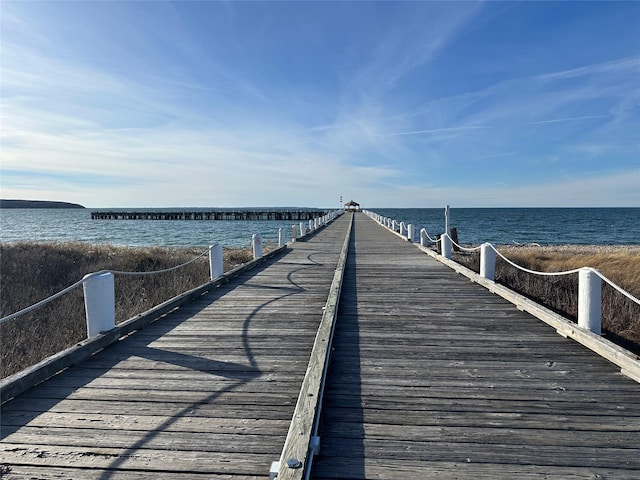 view of dock with a water view and a beach view