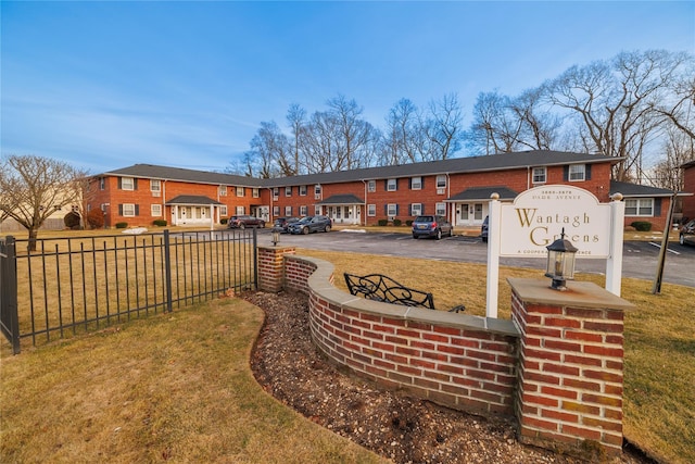 rear view of property with a yard, brick siding, and fence