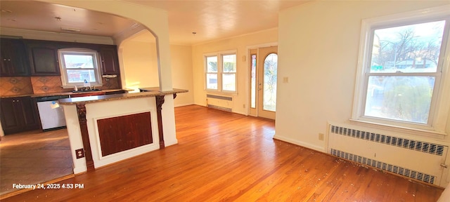 kitchen with light wood-type flooring, decorative backsplash, dishwasher, radiator heating unit, and crown molding