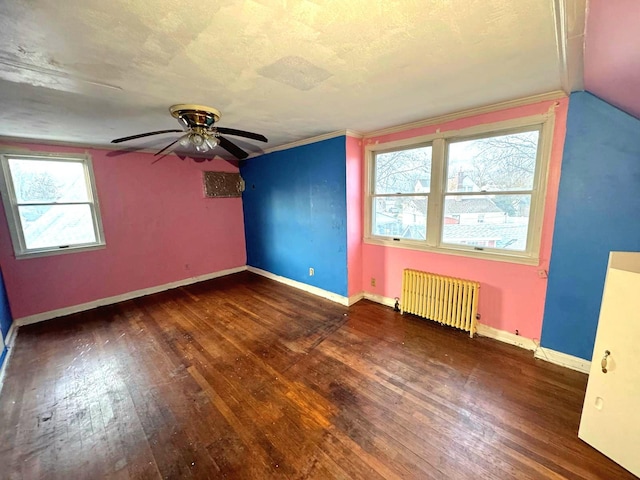 unfurnished room with a textured ceiling, ceiling fan, baseboards, hardwood / wood-style floors, and radiator heating unit