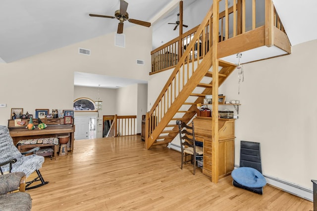 living room with ceiling fan, baseboard heating, wood finished floors, and visible vents