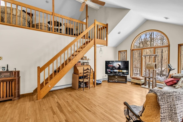 living area featuring stairway, baseboard heating, a ceiling fan, wood finished floors, and high vaulted ceiling