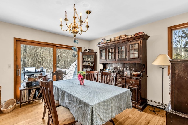 dining space with light wood finished floors, a baseboard radiator, and a chandelier