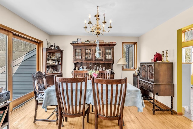 dining space with light wood-type flooring and a notable chandelier
