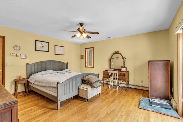 bedroom with visible vents, light wood-style floors, a baseboard heating unit, ceiling fan, and baseboards