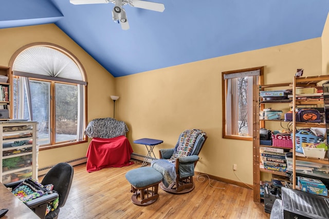 sitting room with a baseboard radiator, vaulted ceiling, baseboards, and wood finished floors