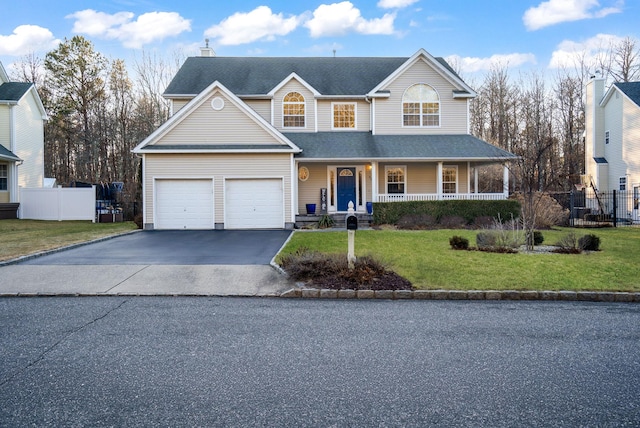 traditional home featuring aphalt driveway, roof with shingles, covered porch, fence, and a front lawn