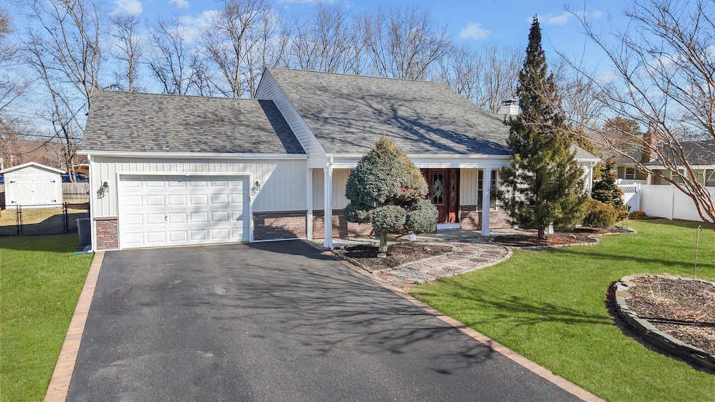 view of front of home with a garage, a front yard, fence, and driveway