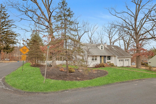 cape cod-style house featuring a front yard, driveway, a chimney, and an attached garage