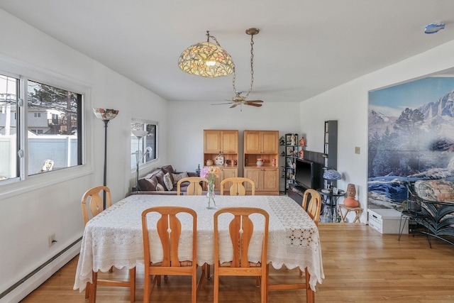 dining space featuring a baseboard heating unit, ceiling fan, and light wood-style floors