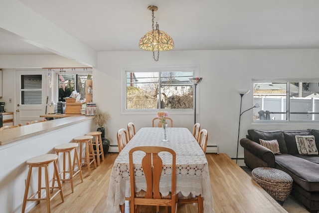 dining room with a baseboard radiator, baseboard heating, and light wood finished floors