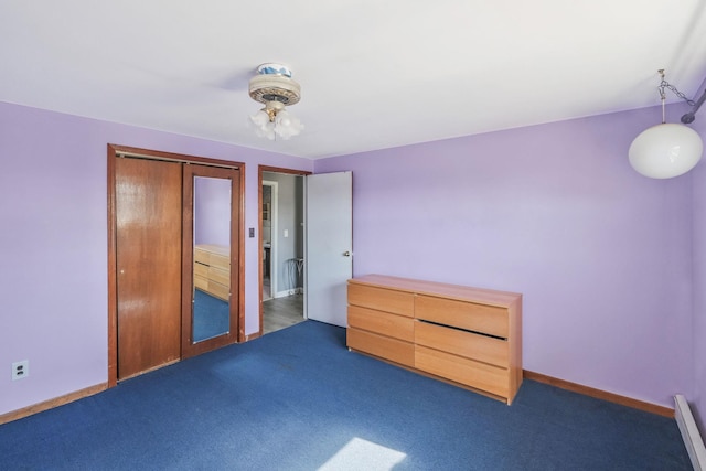 unfurnished bedroom featuring dark colored carpet, a closet, baseboard heating, and baseboards