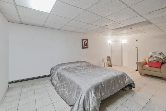 bedroom featuring a paneled ceiling, a baseboard radiator, and light tile patterned flooring