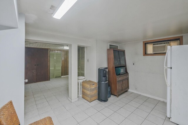 kitchen with light tile patterned floors, an AC wall unit, freestanding refrigerator, and baseboards