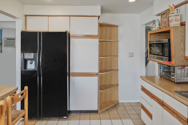 kitchen featuring light tile patterned floors, baseboards, white cabinets, black fridge with ice dispenser, and light countertops