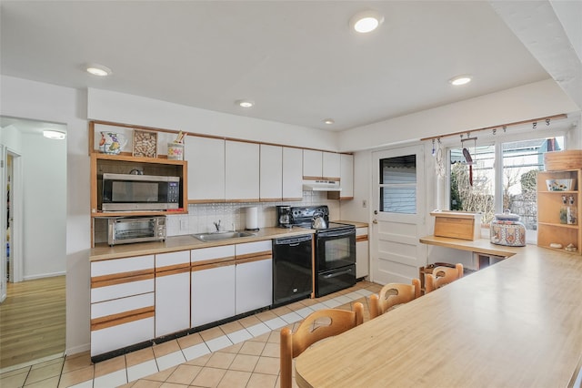 kitchen with light countertops, white cabinetry, a sink, and black appliances