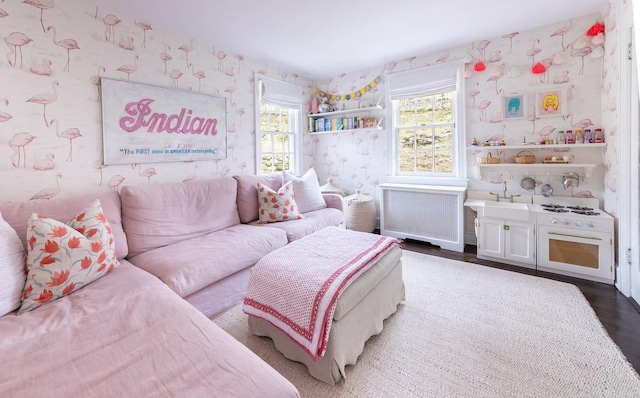 living area featuring wallpapered walls, wood finished floors, and radiator