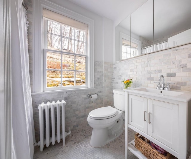 full bath featuring toilet, radiator heating unit, tile patterned flooring, vanity, and tile walls