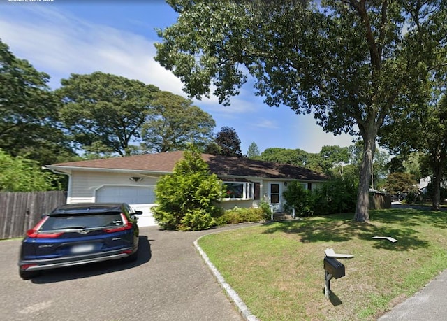 ranch-style house with a garage, driveway, fence, and a front yard