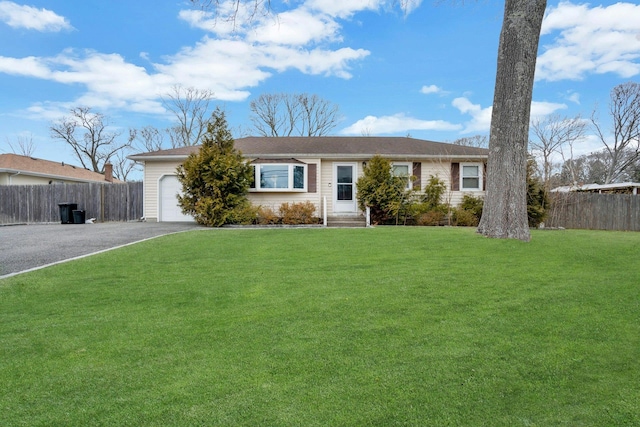 single story home with entry steps, aphalt driveway, an attached garage, fence, and a front lawn