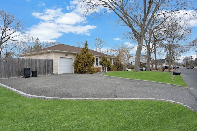 view of front of home featuring an attached garage, aphalt driveway, fence, and a front lawn