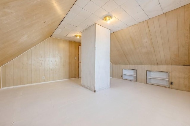 bonus room with vaulted ceiling and wooden walls