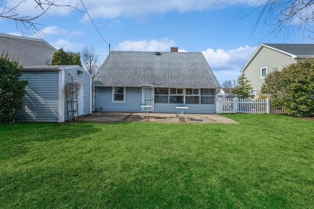 back of property featuring an outbuilding, fence, a sunroom, a yard, and roof with shingles