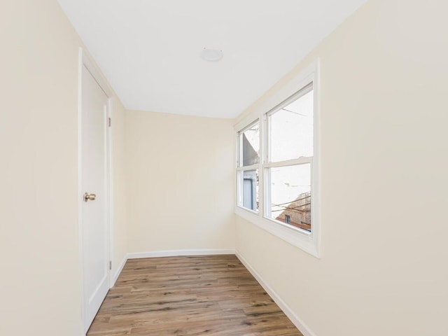 hall with light wood-style floors and baseboards