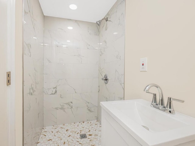 full bathroom featuring a tile shower and a sink