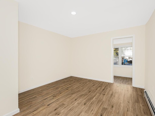 empty room with light wood-style floors, a baseboard radiator, baseboards, and recessed lighting