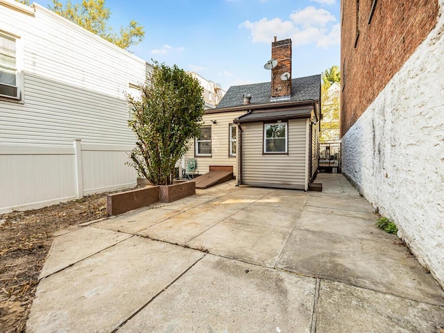 rear view of property with a shingled roof, a chimney, a patio area, and a fenced backyard