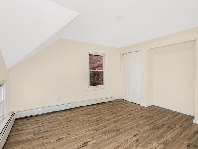 bonus room with lofted ceiling, a baseboard radiator, a baseboard heating unit, dark wood-style flooring, and baseboards