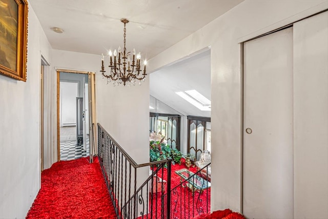 hallway with lofted ceiling with skylight, a chandelier, and carpet flooring