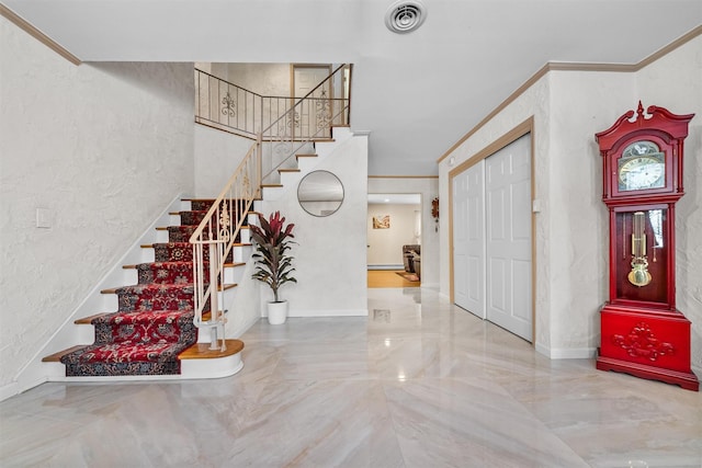 foyer entrance featuring ornamental molding, visible vents, a textured wall, and stairs